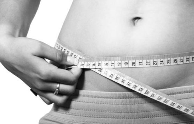 Slim girl measures the size of the waist